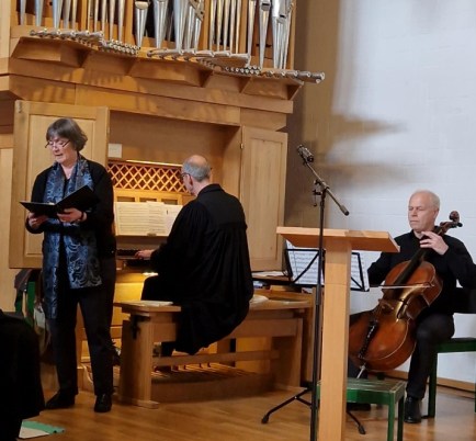 ein Organist, eine Sängerin und ein Cellist musizieren